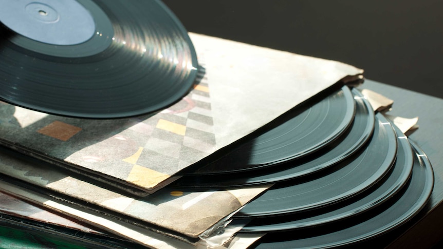 A stack of vinyl records ona  table.