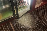 A photo of smashed glass in a beer fridge following a commercial break-in.