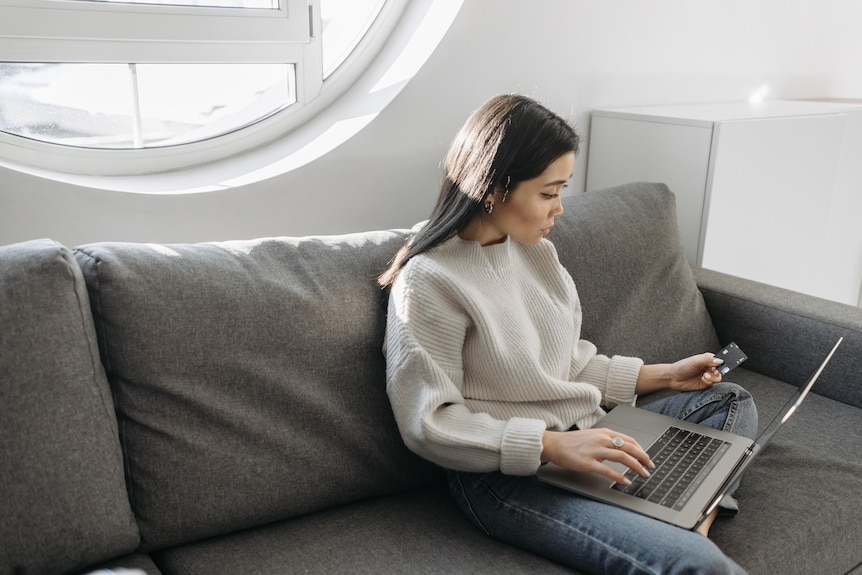 Woman in jumper looking with concern at laptop