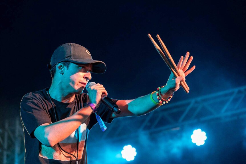 The drummer and rapper DOBBY holding drum sticks and a mic performing on stage