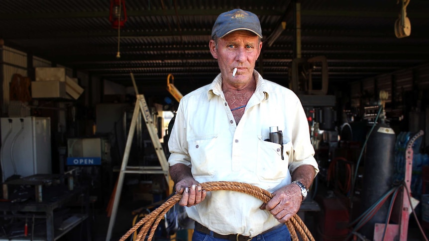 Peter Weston holding his greenhide rope, with a cigarette sitting in the side of his mouth.