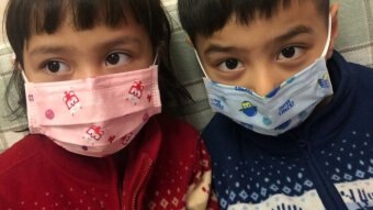 A boy and a girl wear face masks.