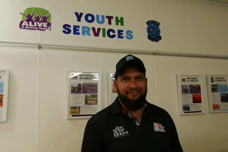 A man smiling in a room below a sign that reads "youth services".