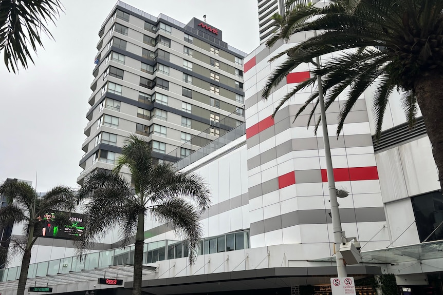 A modern multi-storey apartment block with palm trees in the foreground.