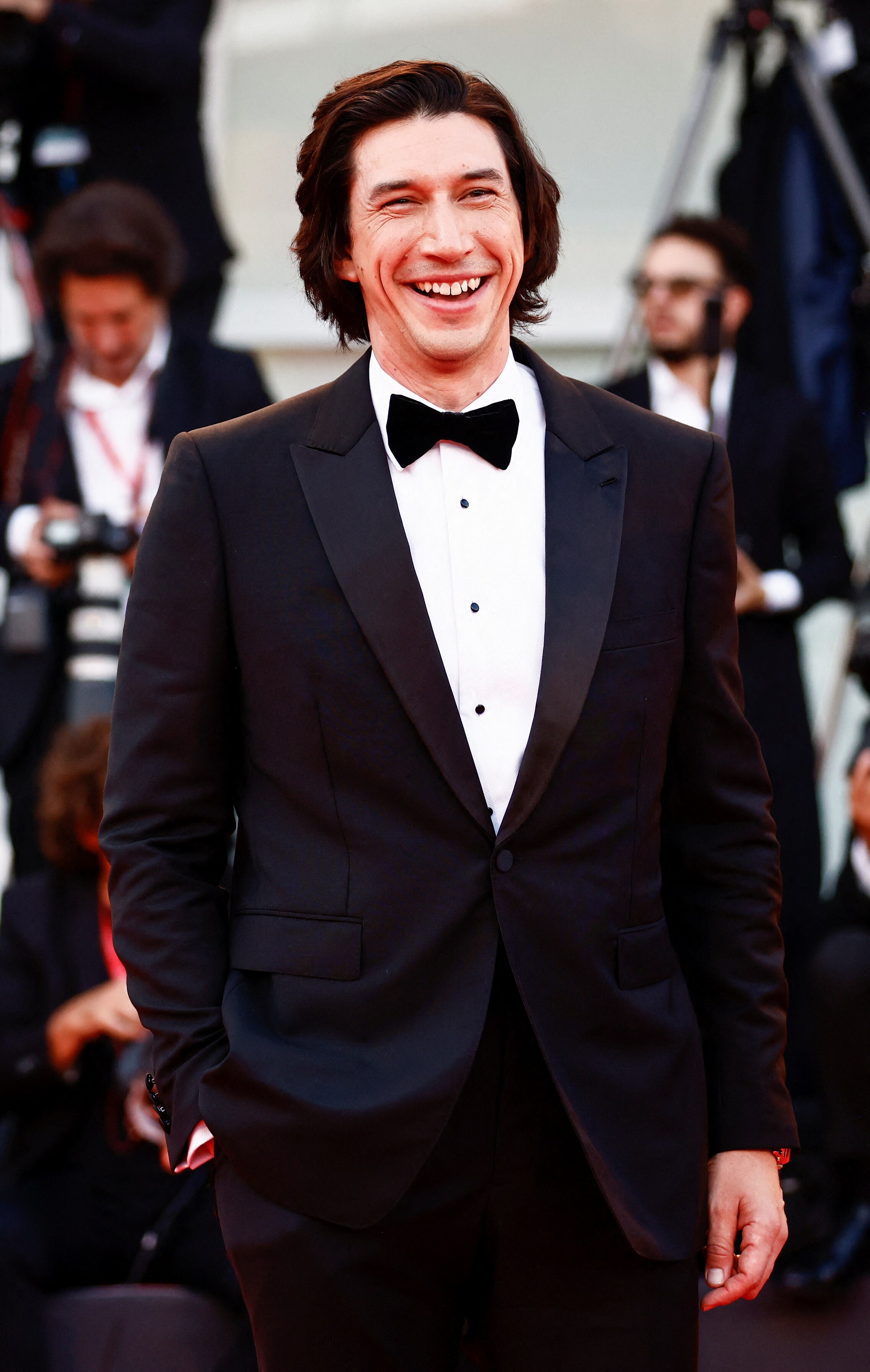 Adam laughs on the red carpet in a suit and bowtie.