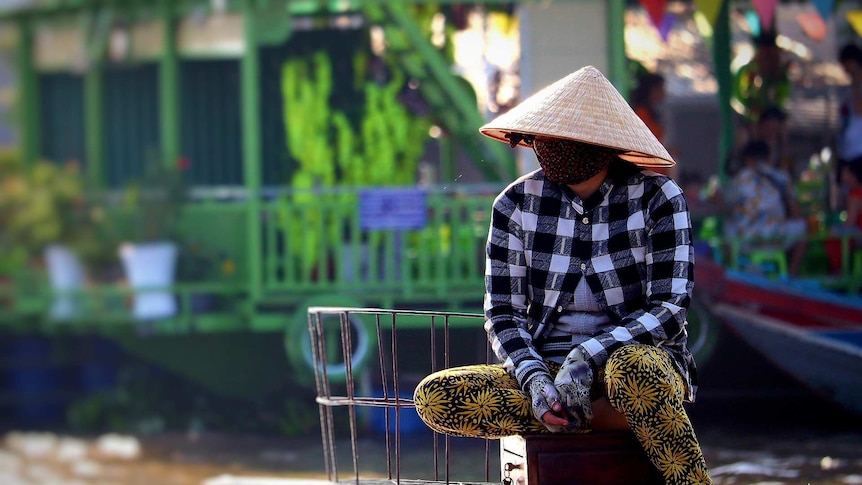 A man wears a traditional Vietnamese hat and face mask as protection from coronavirus.