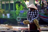 A man wears a traditional Vietnamese hat and face mask as protection from coronavirus.