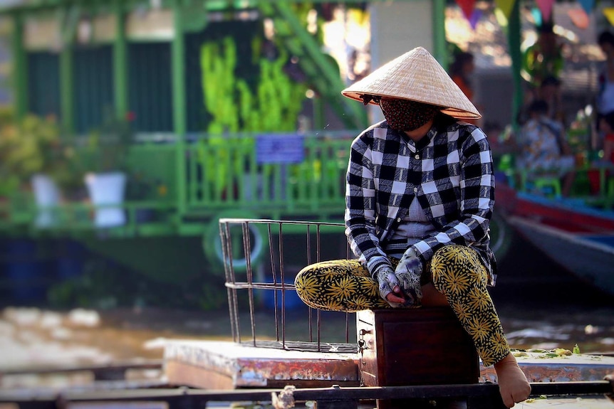 A man wears a traditional Vietnamese hat and face mask as protection from coronavirus.