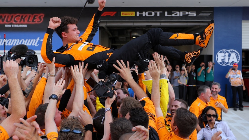 F1 driver Lando Norris crowd surfing on top of his team, after victory