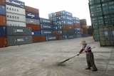 A worker sweeps near containers at a Chinese port.