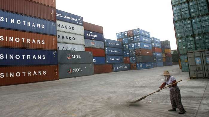 A worker sweeps near containers at a Chinese port.