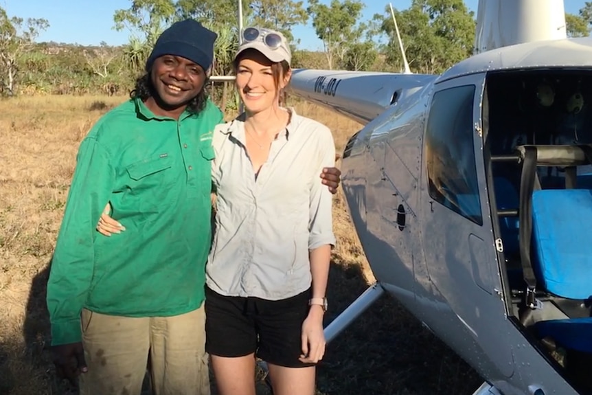 A man and a woman stand next to a helicopter.