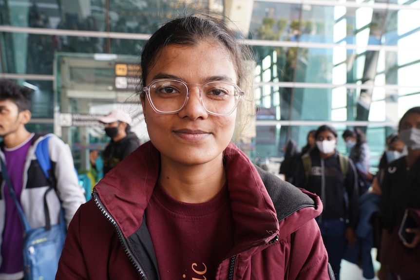 A young Indian woman in glasses and a red hoodie 