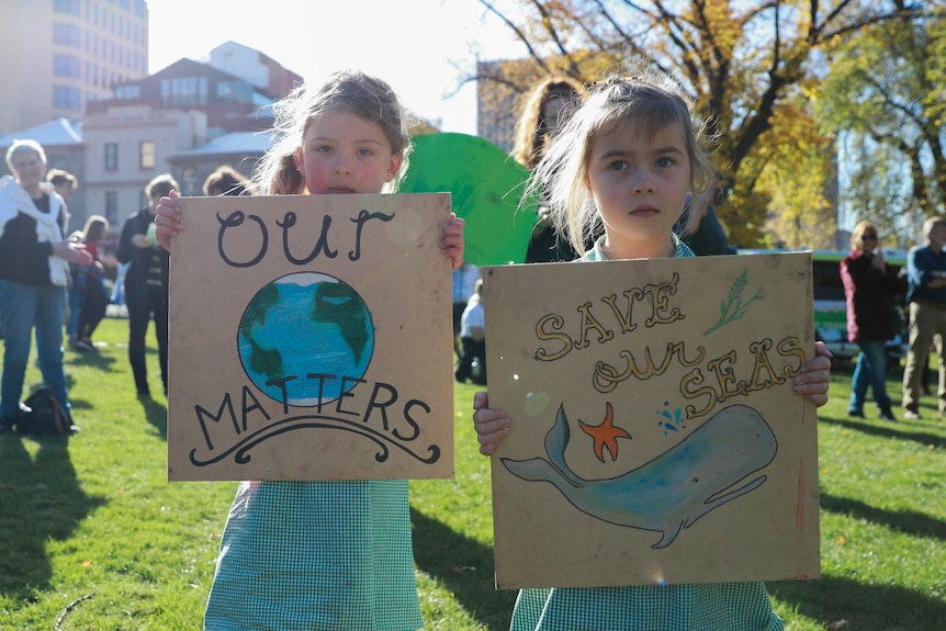 Two young girls stand holding signs at the School Strike 4 Climate event in Hobart.
