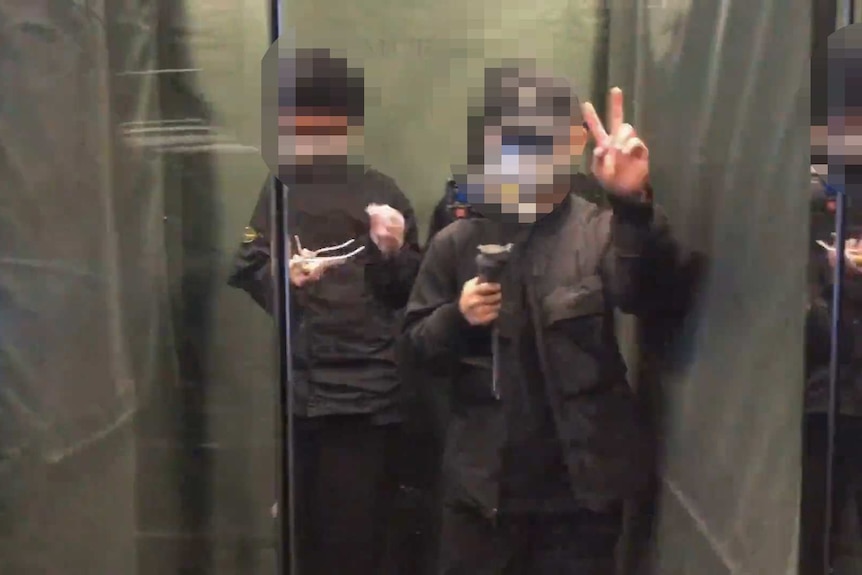 A man does a peace sign while standing in a lift in an apartment building.
