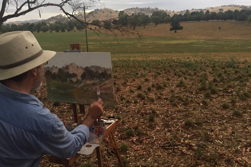 Barry painting a landscape on a canvas.