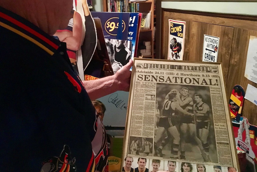 A man holds a framed newspaper clipping