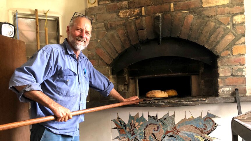 A man bakes bread in a woodfired oven