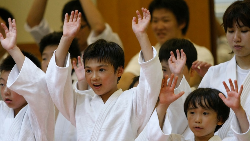 Children who practice judo cheer on Japan's national judo team.
