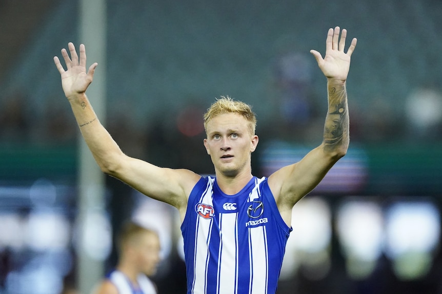 North Melbourne Kangaroos player Jaidyn Stephenson holds his hands up as he stands on the mark.