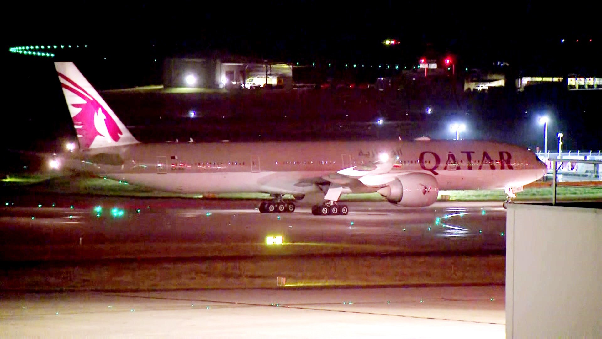 A Qatar Airways plane taxis along the tarmac at Melbourne Airport, on a dark night.