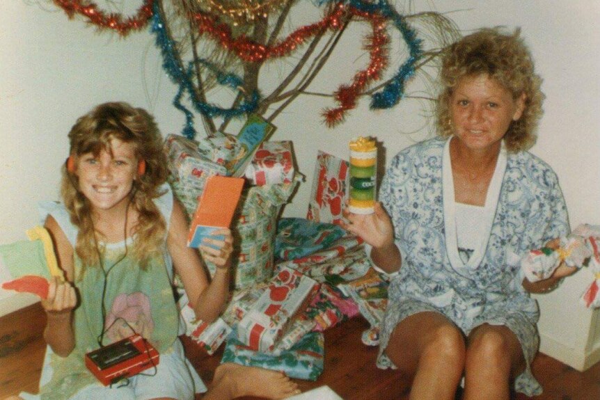 Tracey and her mum in front of a Christmas tree.