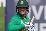 Quinton de Kock carries his bat and takes off his gloves as he leaves the field