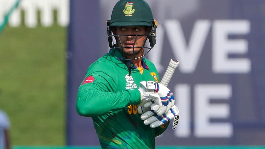 Quinton de Kock carries his bat and takes off his gloves as he leaves the field