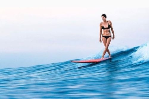 A woman standing on her surf board on the water