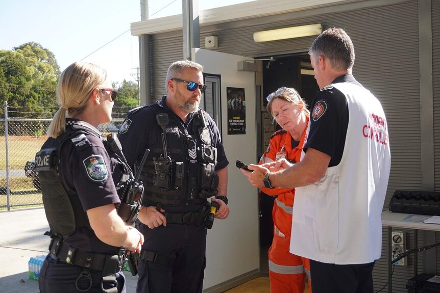 The SES, firies and police look at a phone together to discuss the bushfires.