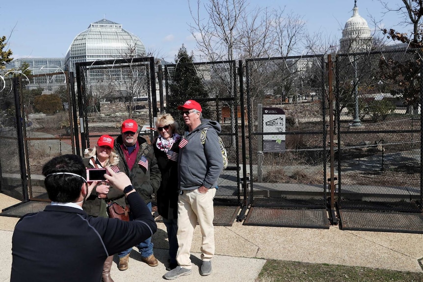 Supporters of Donald Trump get their phot taken near the black fence around the US Capitol Building