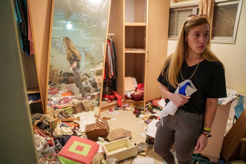 A woman stands in a ransacked room
