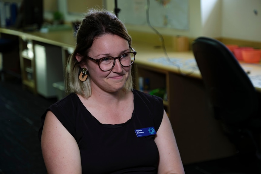 Woman with glasses sits side on to the camera 