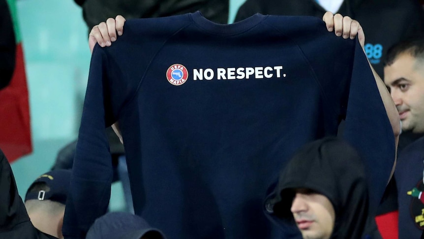 A football fan holds up a jumper with the motto "No respect" at an international match.