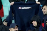 A football fan holds up a jumper with the motto "No respect" at an international match.