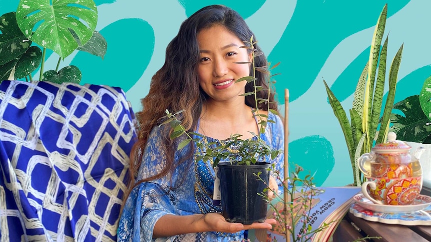 Sherry Sun on her balcony holding a pot plant that's part of her apartment's vegetable patch.