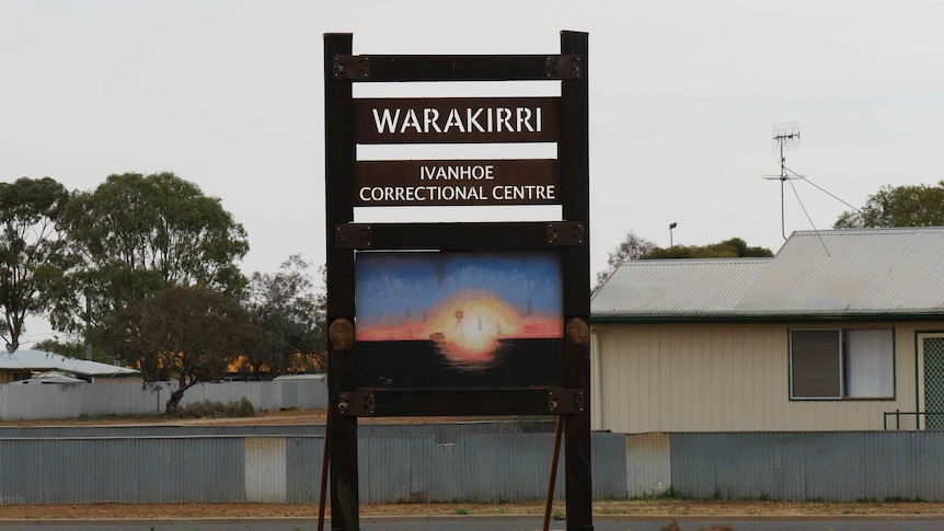 A sign reading 'WARAKIRRI IVANHOE CORRECTIONAL CENTRE' with a colourful Indigenous artwork underneath.