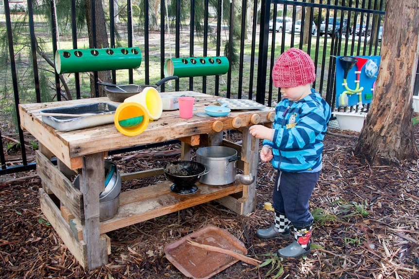 Boy playing with mud kitchen