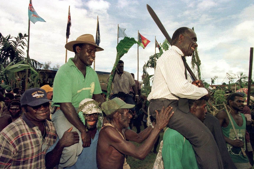 Sam Kauona, commander of the BRA, and Gerard Sinato, Premier of Bougainville, are carried on the shoulders of former guerrillas.