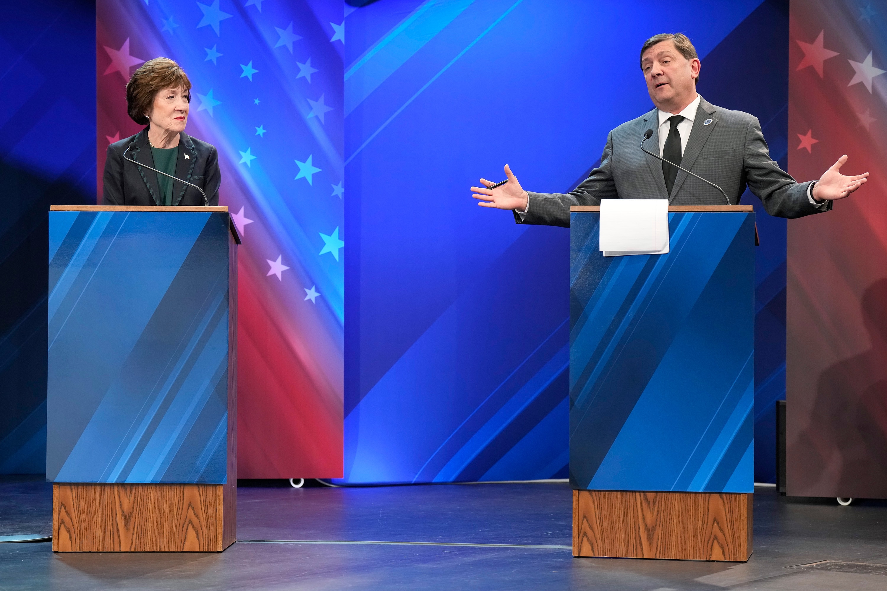 Susan Collins stands behind a debate podium and looks toward Troy Jackson.