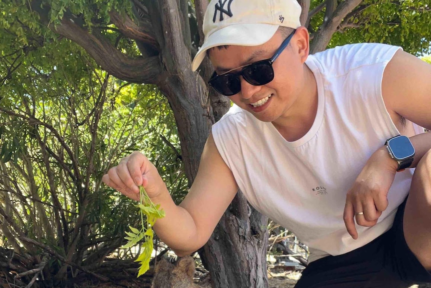 Man poses for picture with a quokka