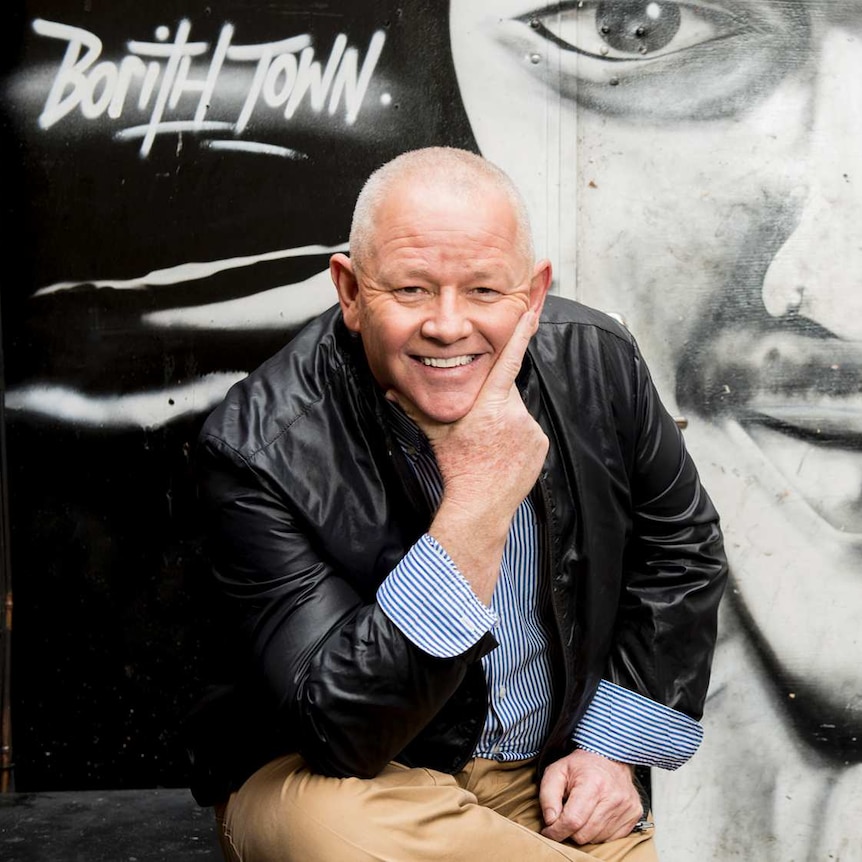 Spence Denny in front of a spray painted mural.