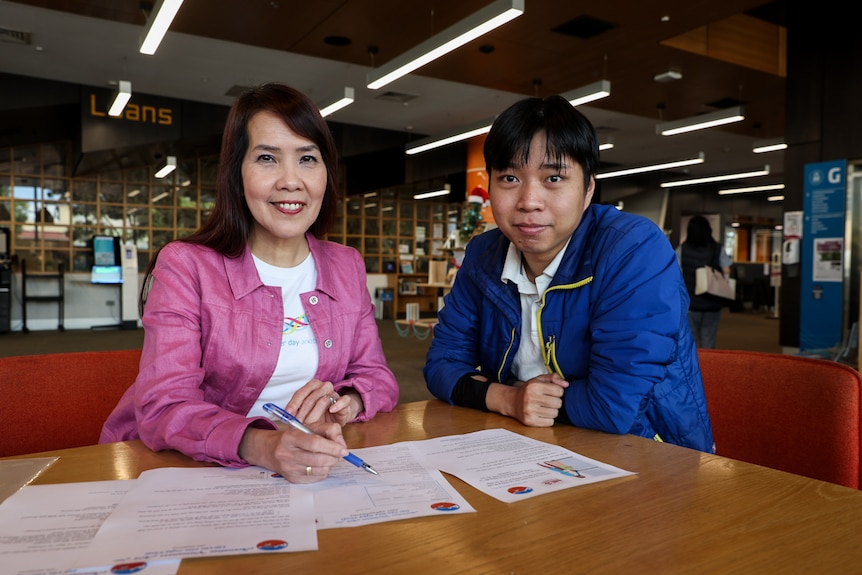 Mai Nguyen y Arthur Nguyen fotografiados con documentación para préstamos sin intereses en la biblioteca Sunshine