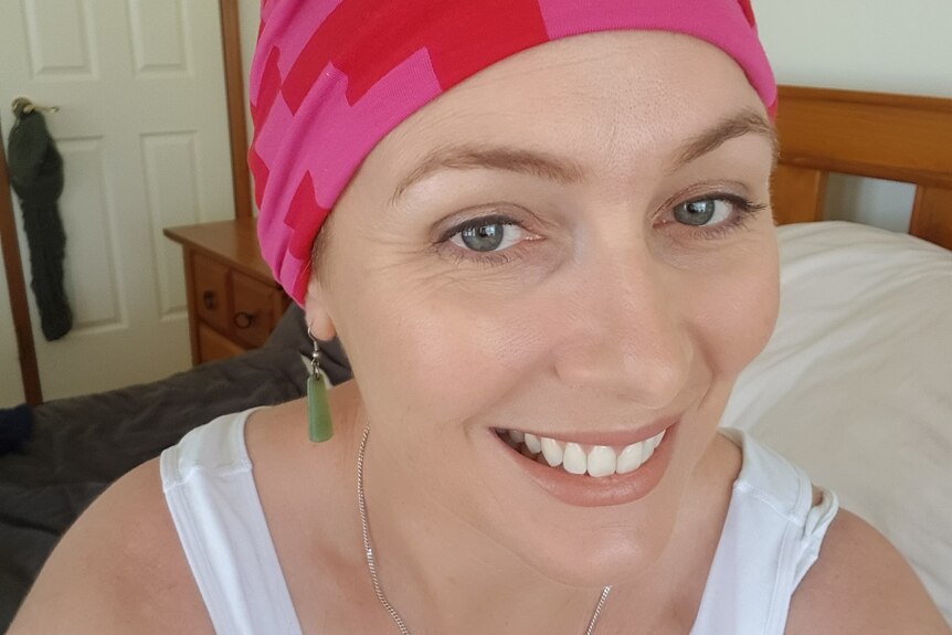 Narelle smiling at the camera wearing a pink head scarf.