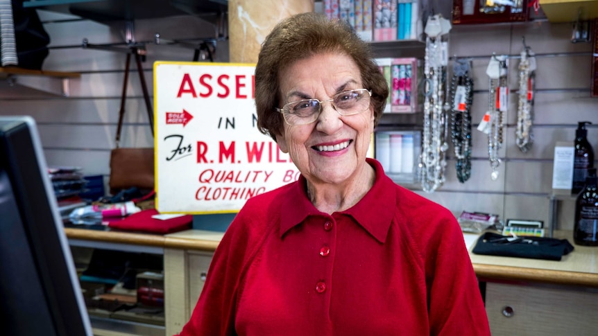 An elderly lady stands inside a retail store.