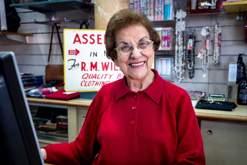 An elderly lady stands inside a retail store.