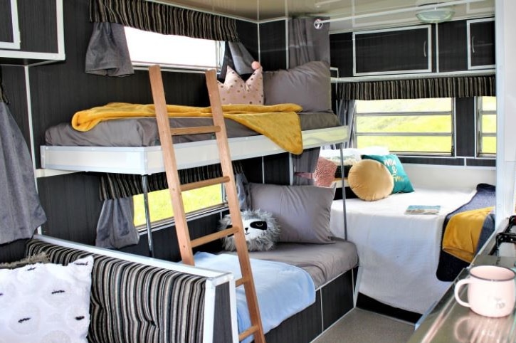 The interior of a caravan with bunk beds and colourful pillows.