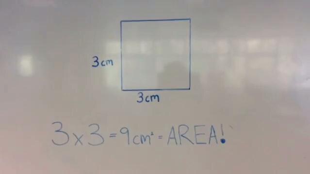 Whiteboard shows drawing of square and sum to calculate area of square