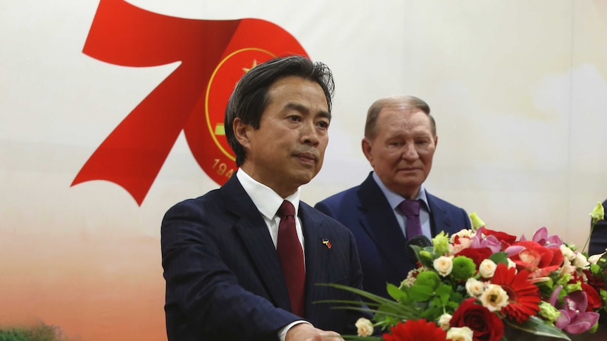 A man in a suit stands at a lectern.