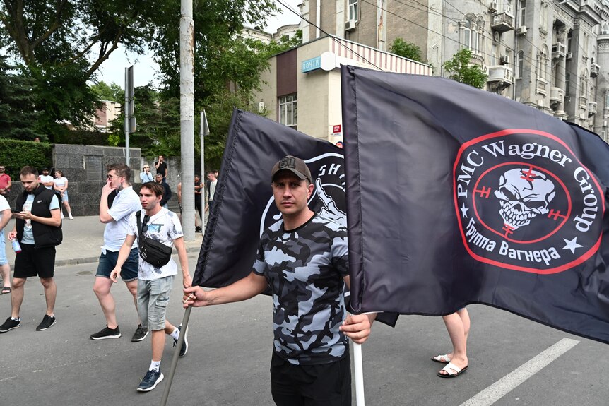 A supporter of Wagner private mercenary group holds flags near the headquarters of the Southern Military District.